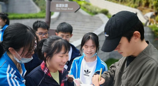 朱一龙衣着朴素回母校探望 获师生簇拥签名合照