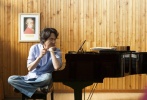 韩石圭盘腿坐在椅子上，用小竹棍百无聊赖地拨弄着钢琴。