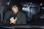延正勋饰演的男主人公K脸上带着伤疤，坐在车里，手中拿着手枪，表情凝重。