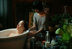 严正花躺在浴缸里，而饰演她后辈的金孝珍正在为她冲洗头发。