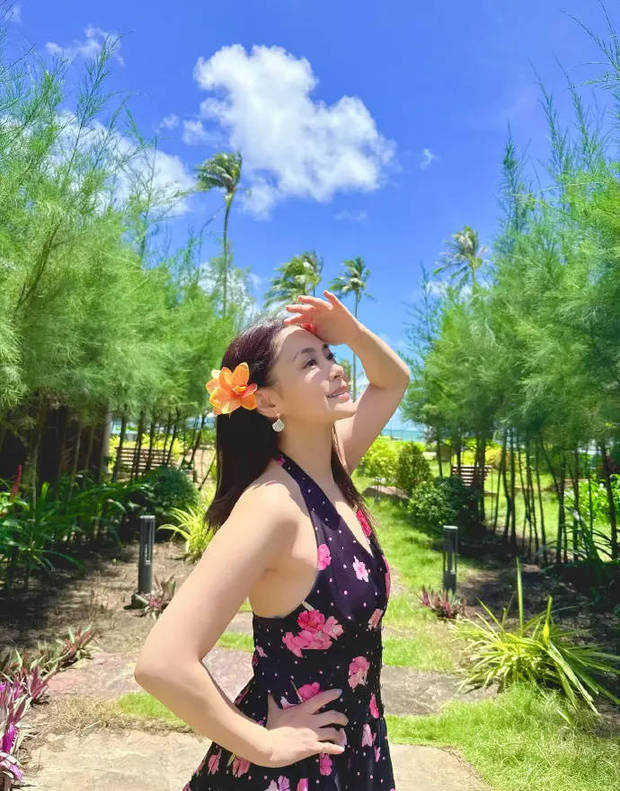 鐘欣潼穿碎花掛脖裙，發(fā)別橙花，手搭額頭眺望。