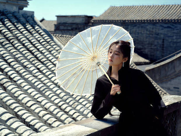 關(guān)曉彤憑欄持傘，眼神悠遠(yuǎn)。